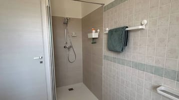 A bathroom with a shower, sink, and towel rack.