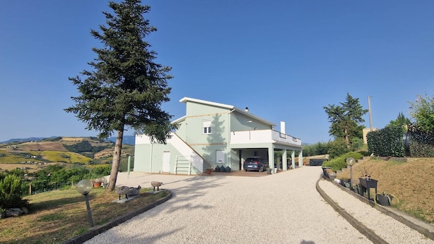 A two-story building with a driveway leading to a garage. - Serene Ground-floor Apartment With Private Pool in Castilenti (Castilenti)