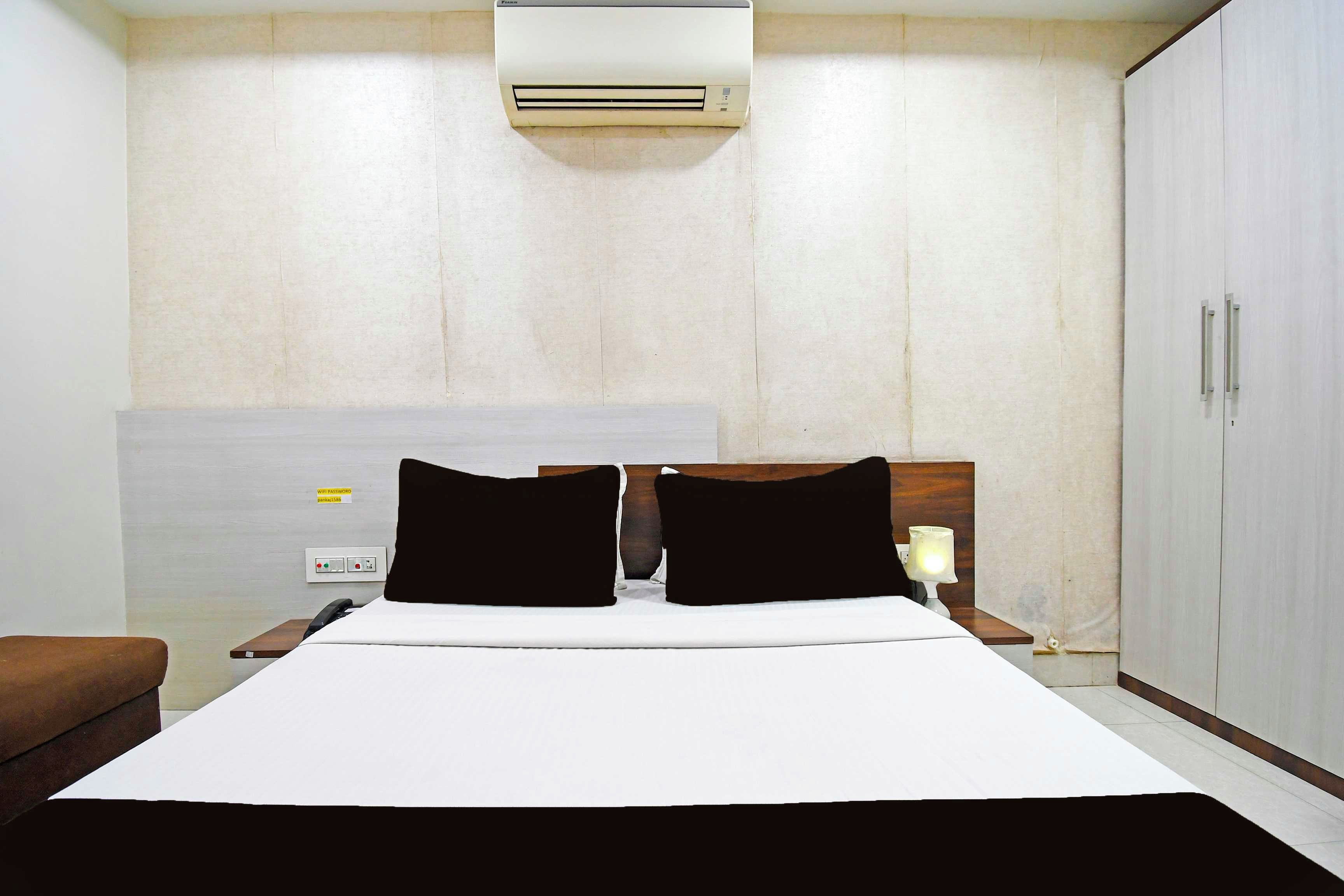 Ein Hotelzimmer mit Bett, Nachttisch, Lampe, Kleiderschrank und Klimaanlage.