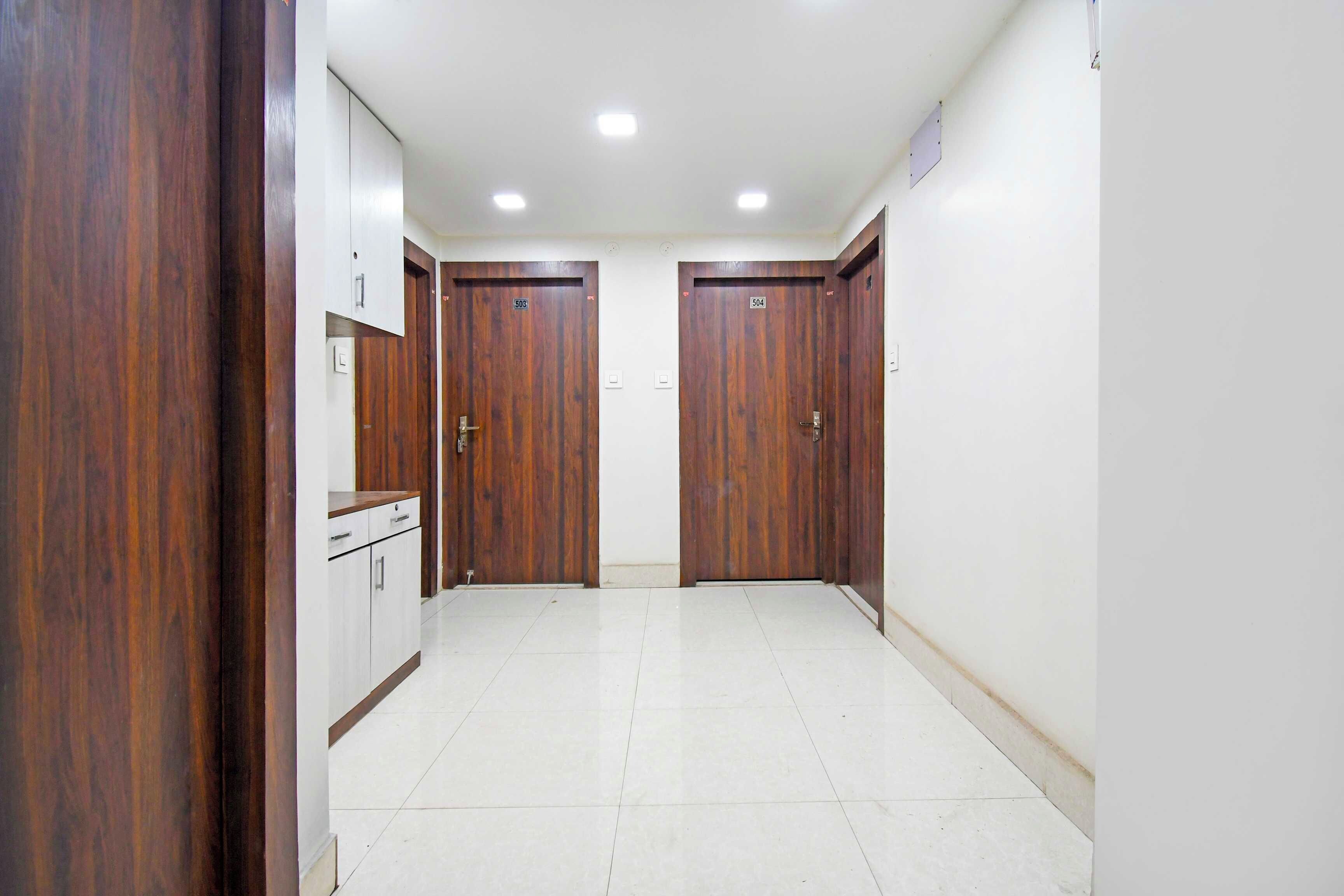 A hallway with two wooden doors, a white cabinet, and a tiled floor.