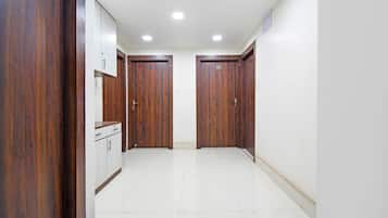 A hallway with two wooden doors, a white cabinet, and a tiled floor.