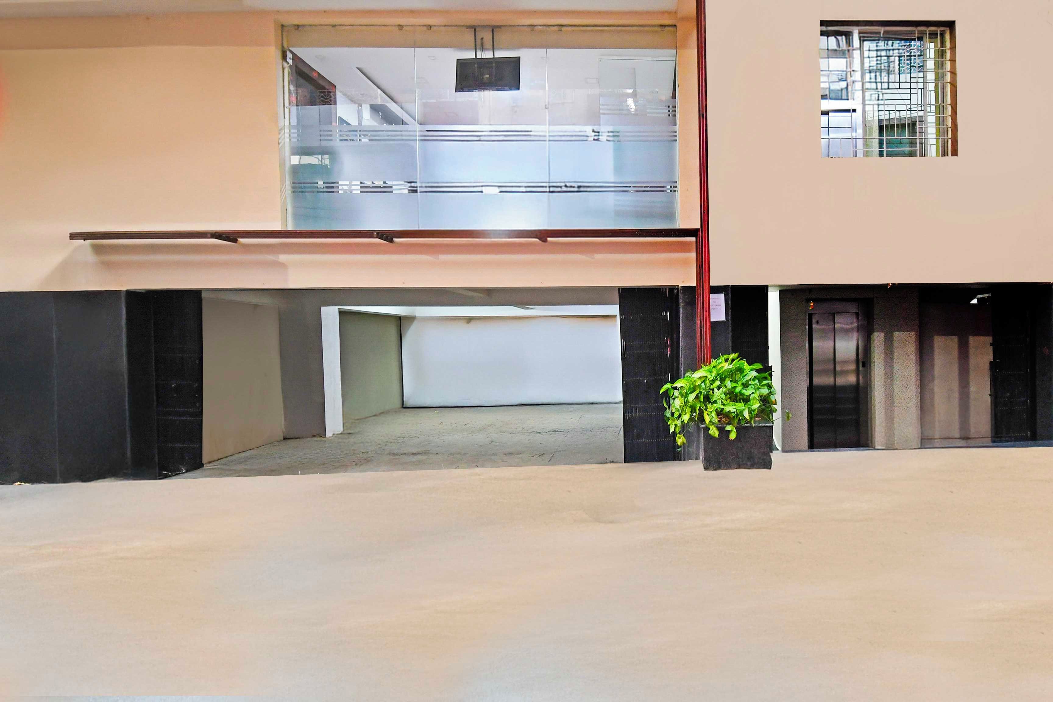 A building with a covered entrance, a visible elevator, and a potted plant.