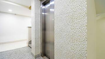 Un ascensor en un edificio con pared texturizada y suelo de baldosas.