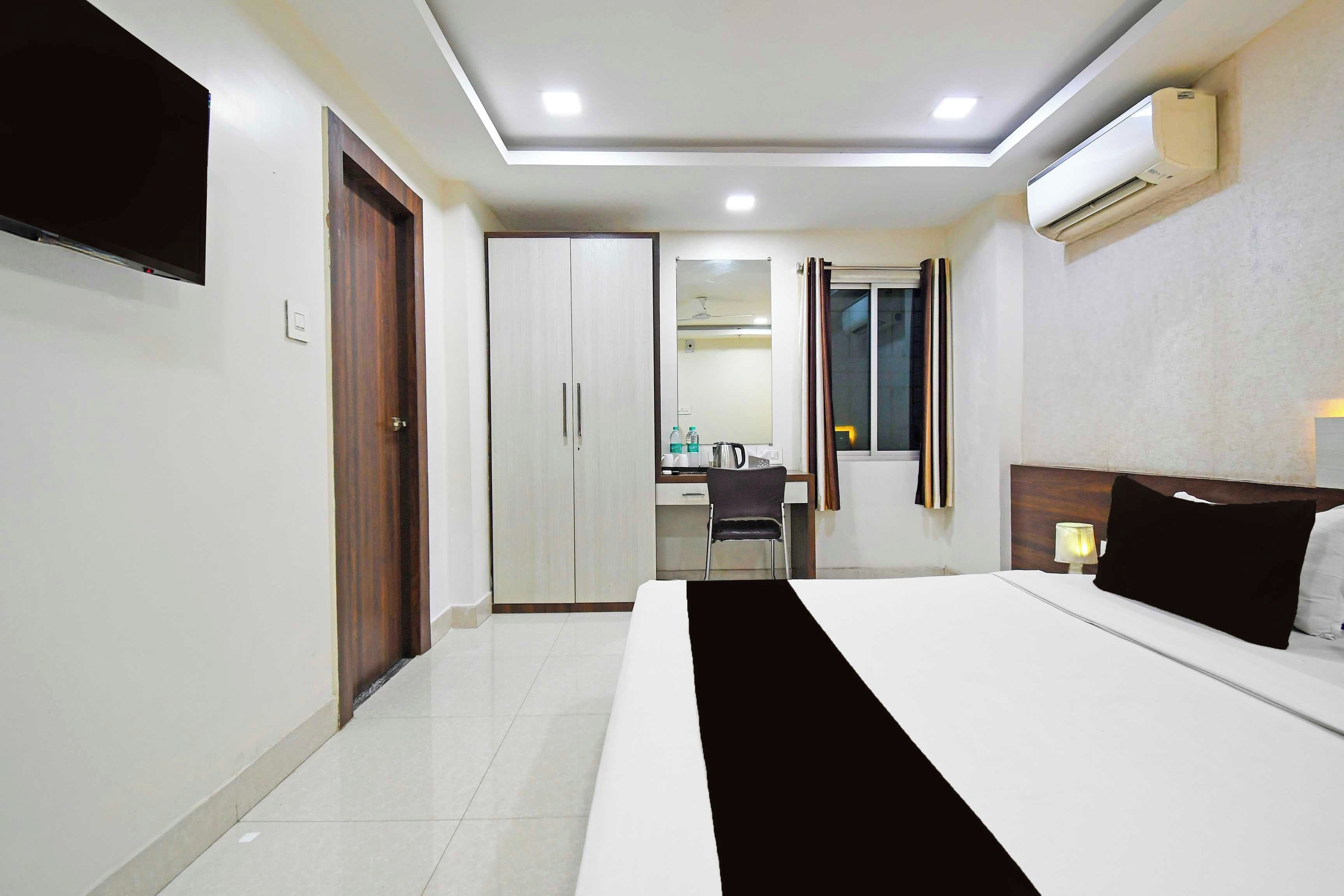 A hotel room with a bed, a desk, a chair, and a wardrobe.
