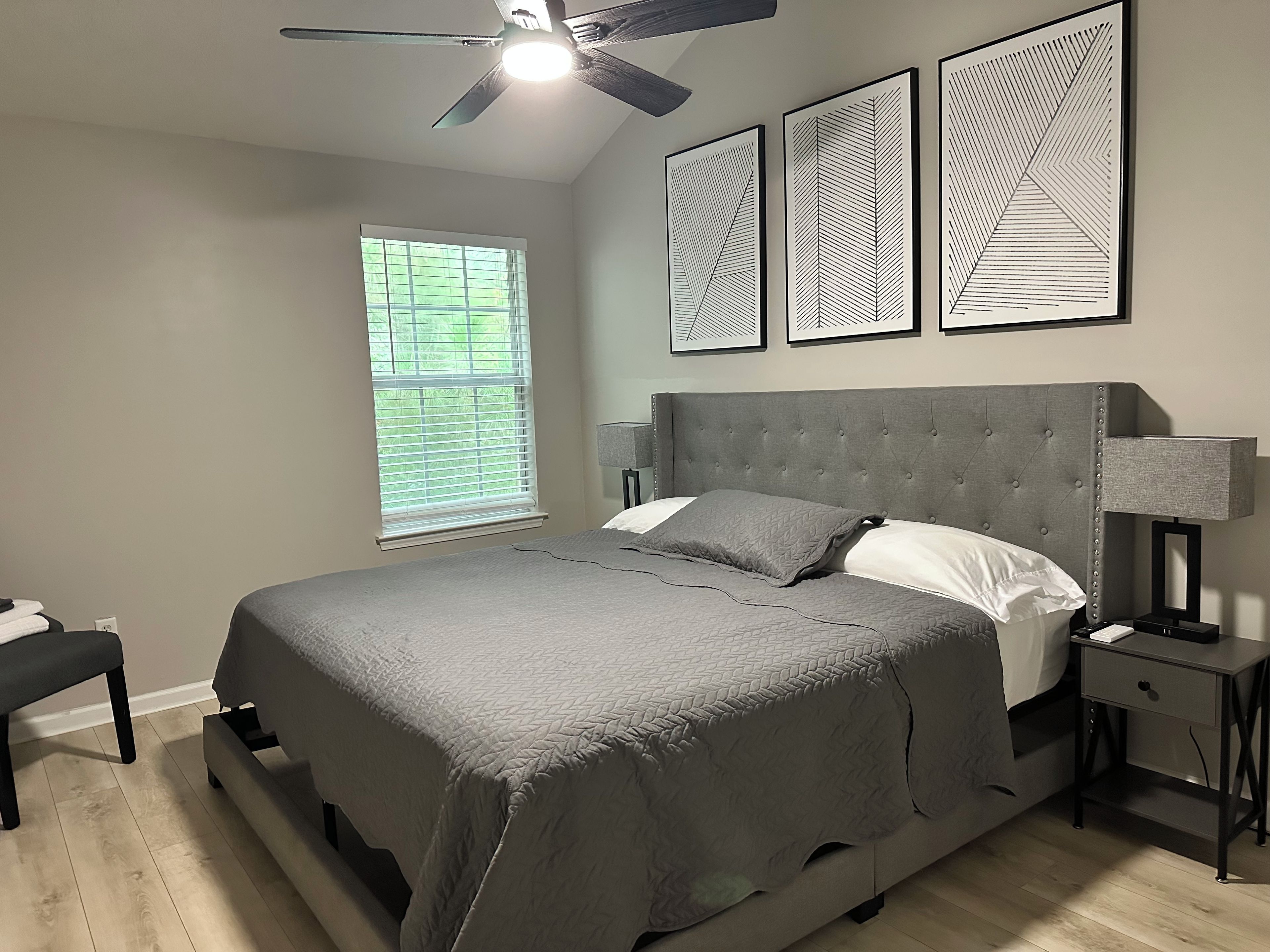 Une chambre à coucher avec un lit, une table de chevet, une lampe et un ventilateur de plafond.