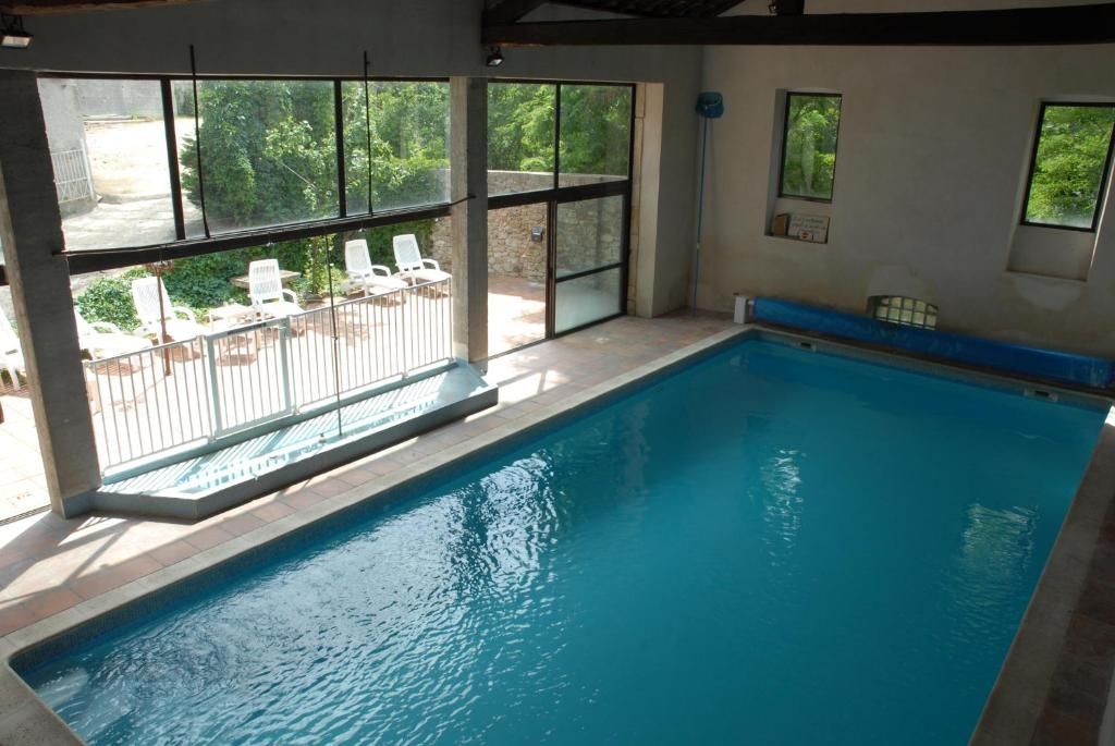An indoor swimming pool with clear glass walls, a tiled deck, and a view of the outdoors.