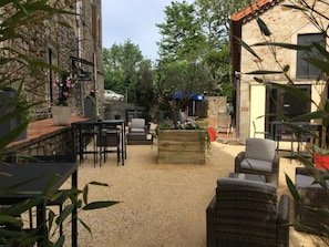 Un patio al aire libre con paredes de piedra, mobiliario exterior y suelo de grava.