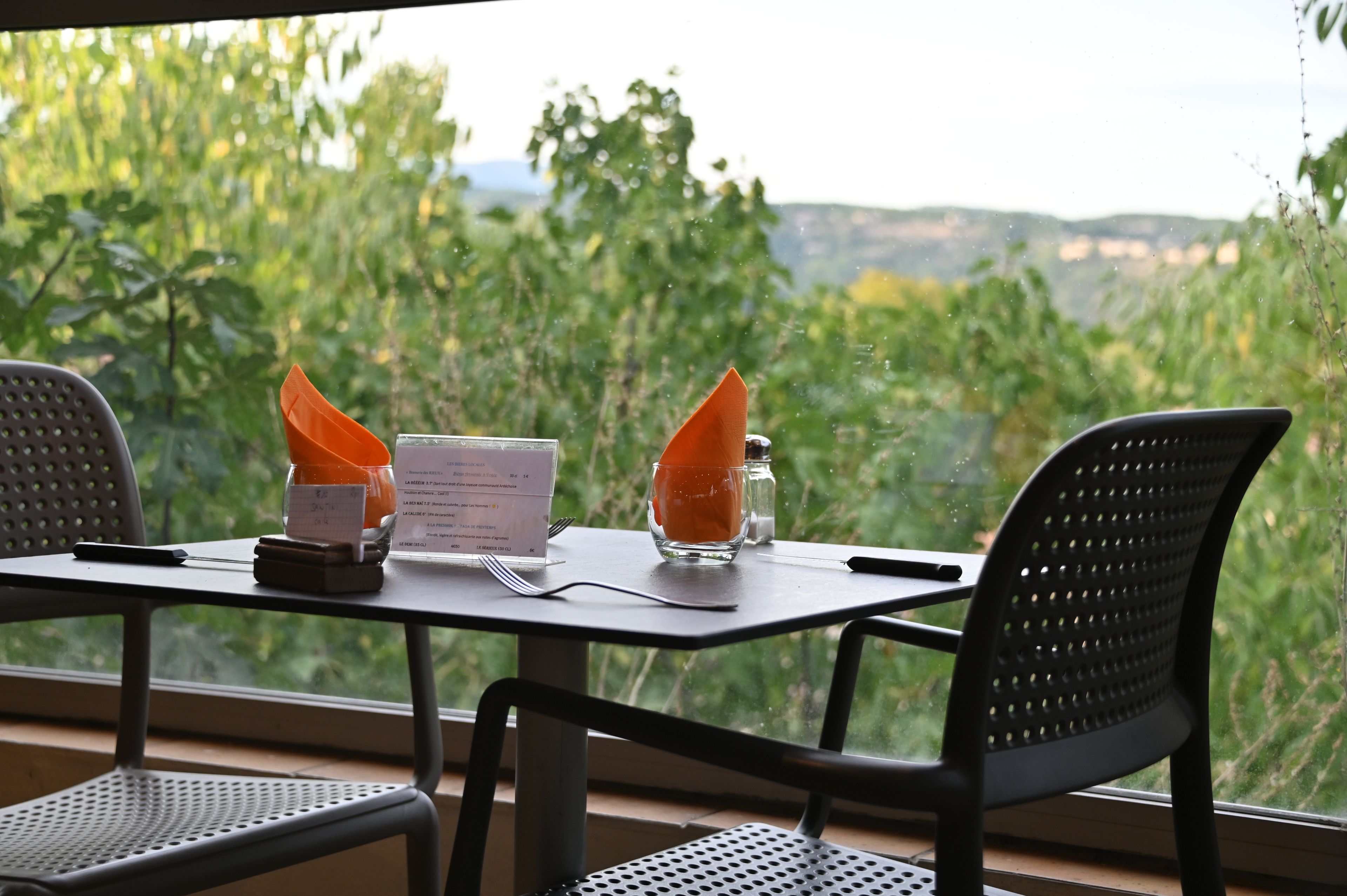 A table set for two with a menu, a glass of orange juice, and a salt shaker.