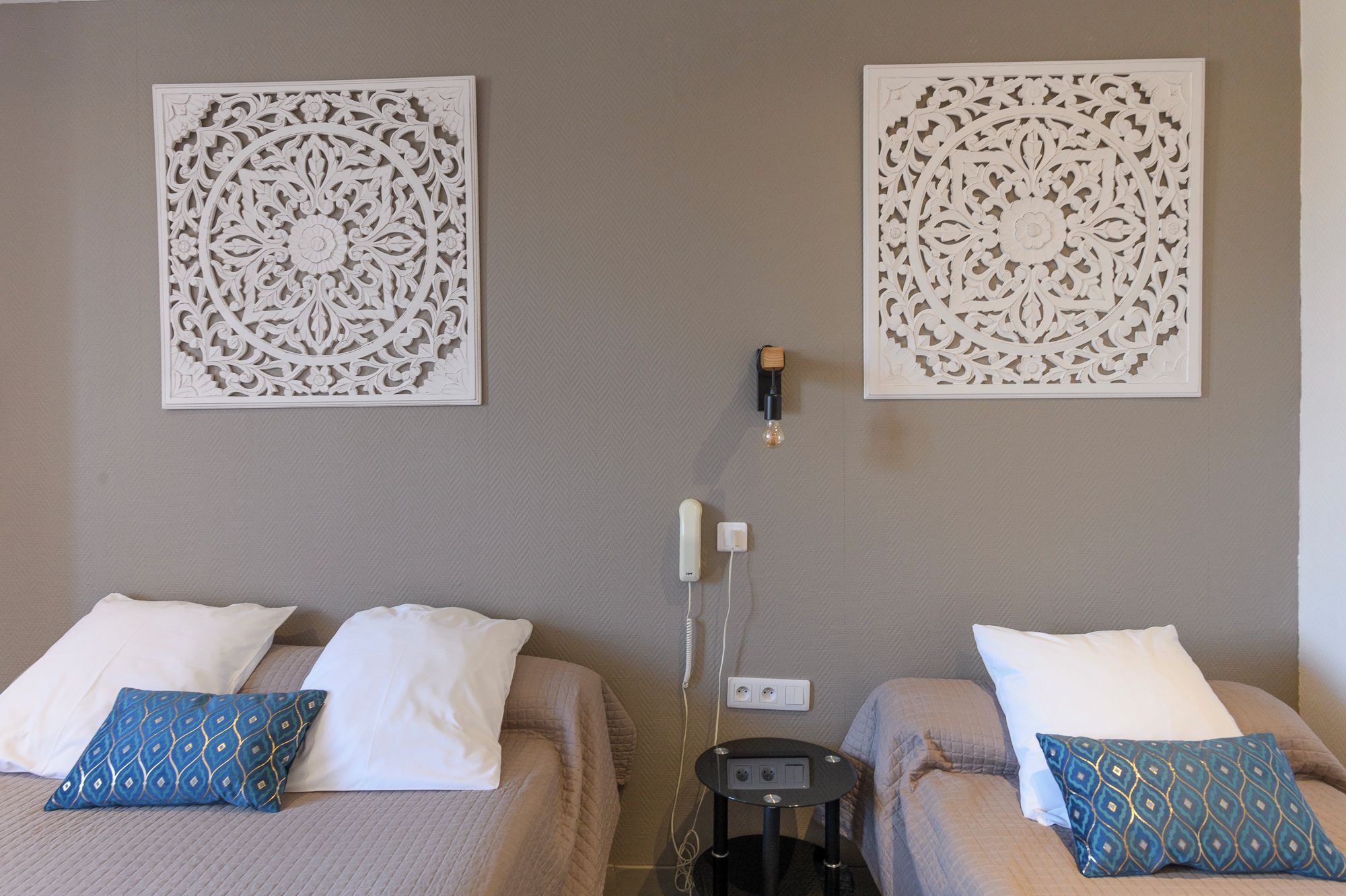 A hotel room with two beds, each with a pillow and a wall-mounted decorative panel.