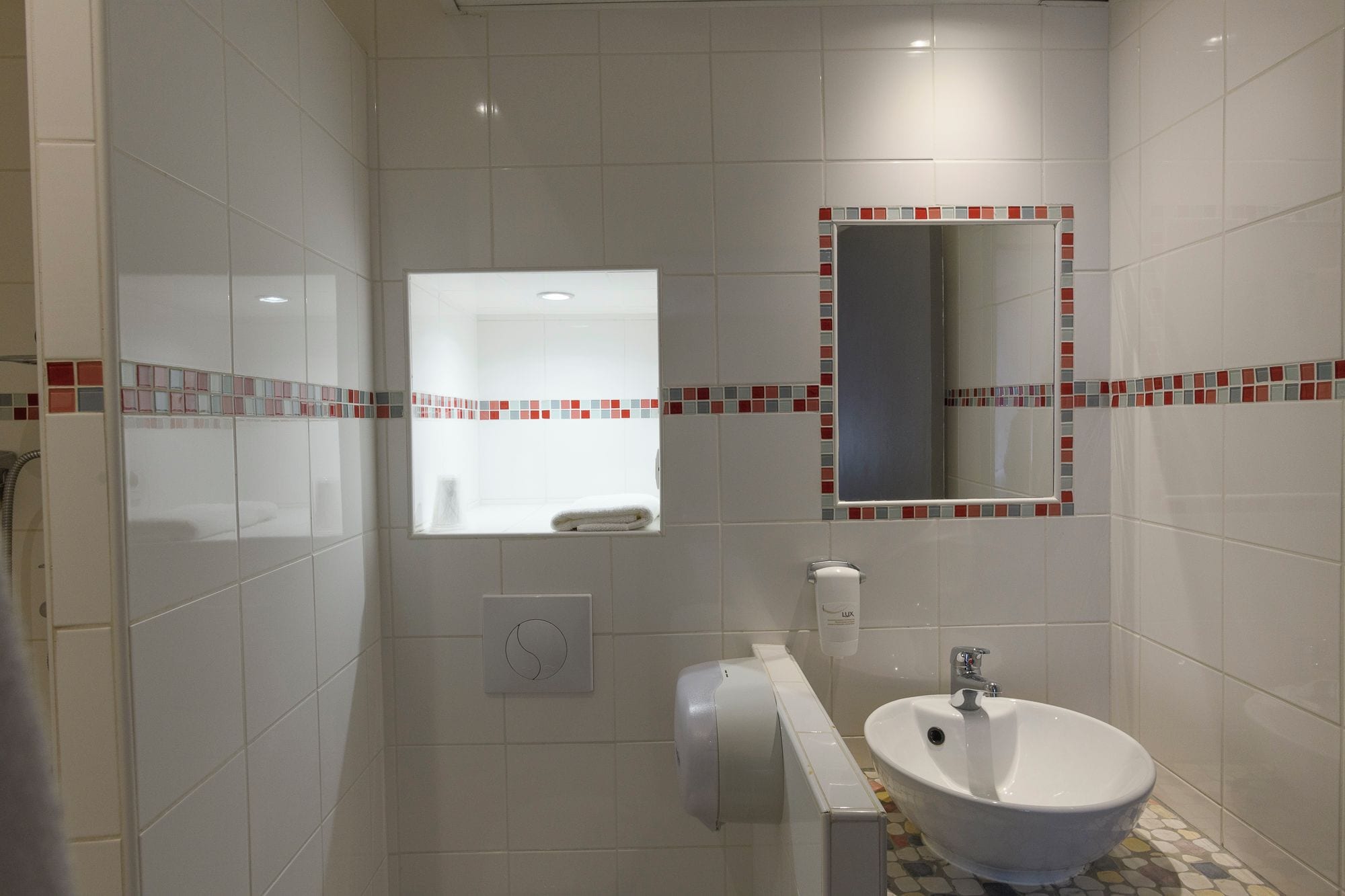 A bathroom with a white sink, a mirror, and a toilet.