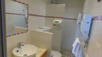A bathroom with a sink, toilet, shower, and a mirror.