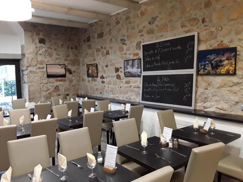 Een restaurantinterieur met stenen muren, gedekte tafels met witte servetten en zwarte menukaarten.