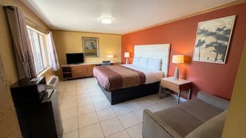 Une chambre d’hôtel avec un lit, un bureau, une chaise, une télévision et un tableau au mur.