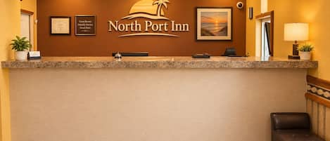 A reception desk with a framed certificate, a clock, and a framed picture of a sunset.