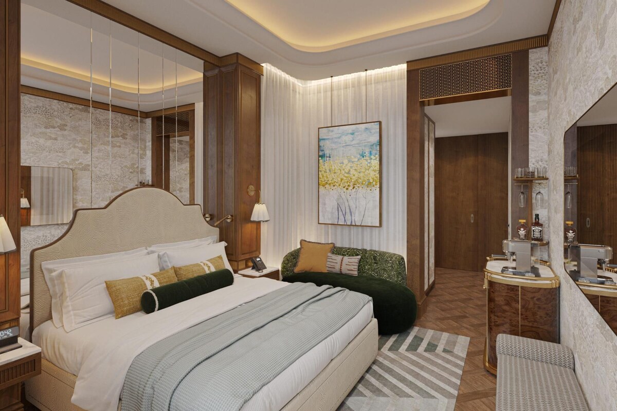 A hotel room with a large bed, a sitting area with a sofa, a desk with a mirror, and a large window.