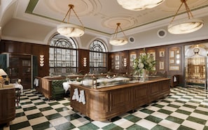 A spacious kitchen with a large island, wooden cabinetry, and a checkered floor. - The WestDill Mayfair Hotel London, Colbert Collection (London)