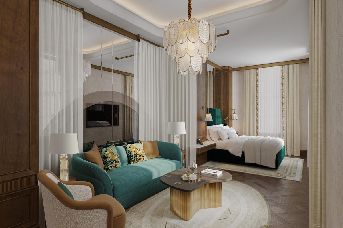A hotel room with a large bed, a sofa, a coffee table, and a chandelier.