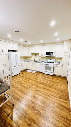 A kitchen with white cabinets, a refrigerator, a microwave, a stove, and a sink. - Cozy Retreat On The Eastside Estate (sleeps 4) (Greater Napanee)