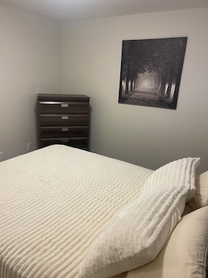 A bedroom with a bed, a dresser, and a wall-mounted picture. - Adorable 1-bedroom condo in beautiful Calgary perfect for your stay (Calgary)