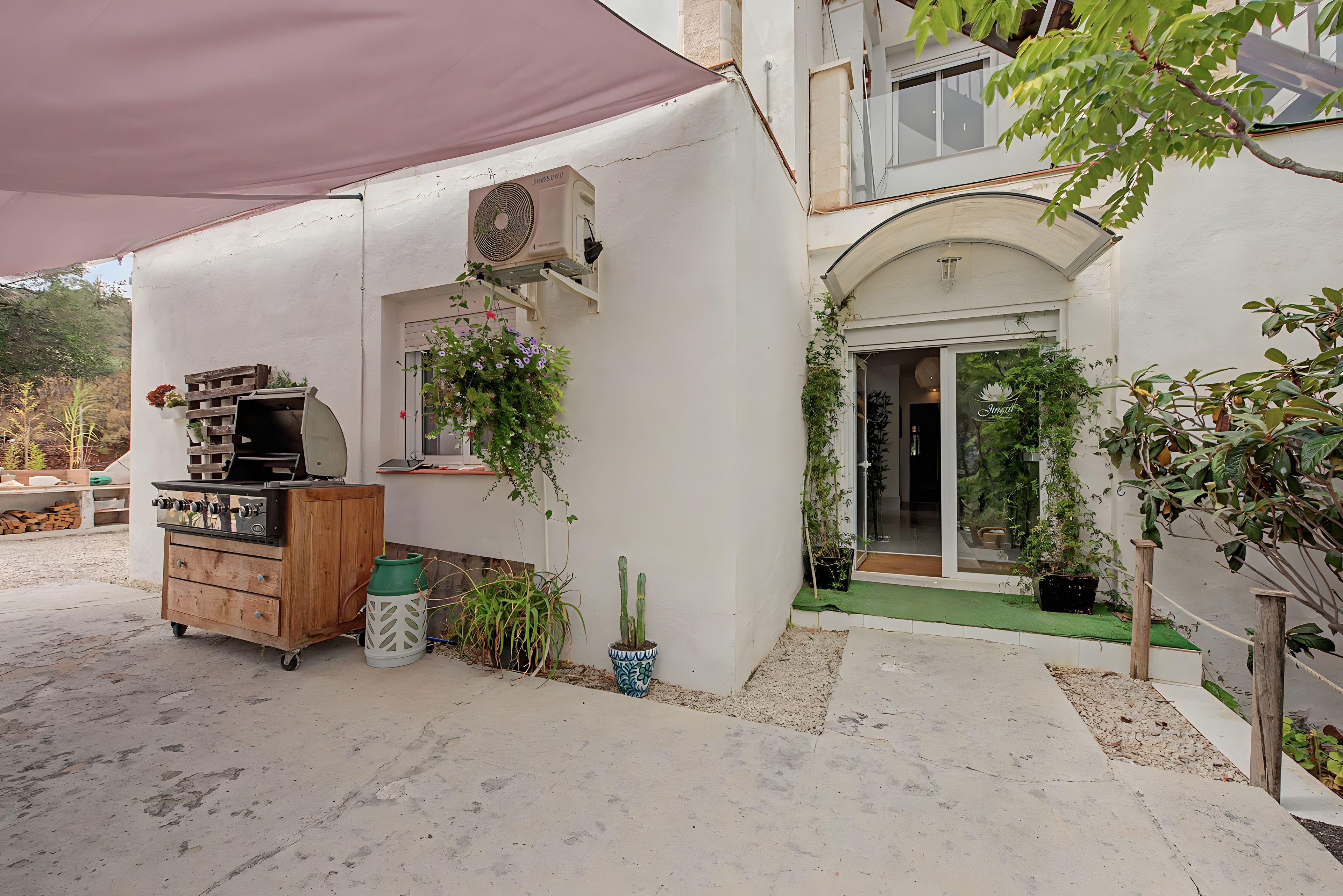 Un espace patio aménagé avec un barbecue, des plantes en pot et un climatiseur Samsung.