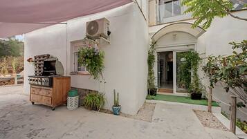 Un espace patio aménagé avec un barbecue, des plantes en pot et un climatiseur Samsung.