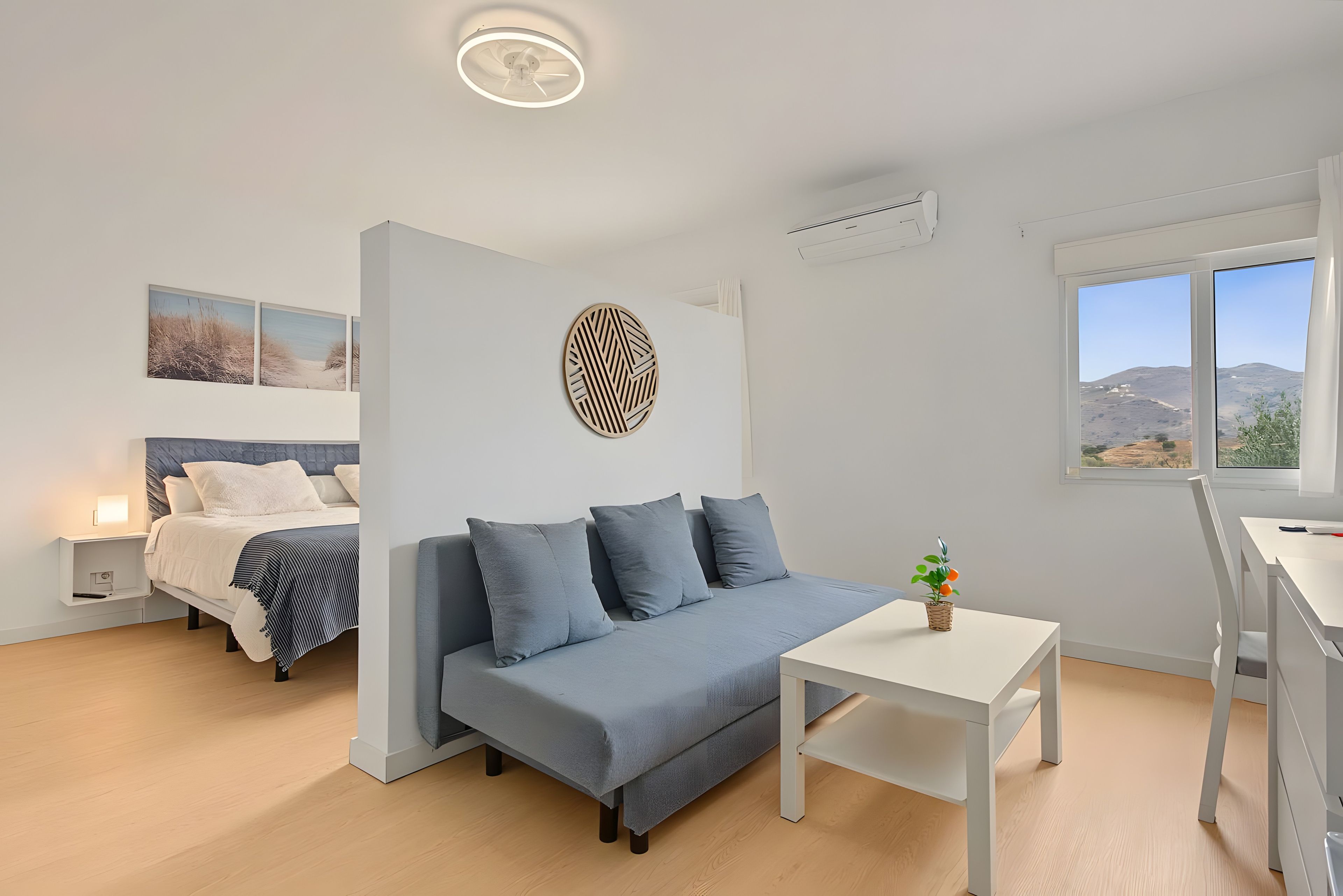 Une chambre moderne avec un lit, un canapé, une petite table et une fenêtre donnant sur un beau paysage.