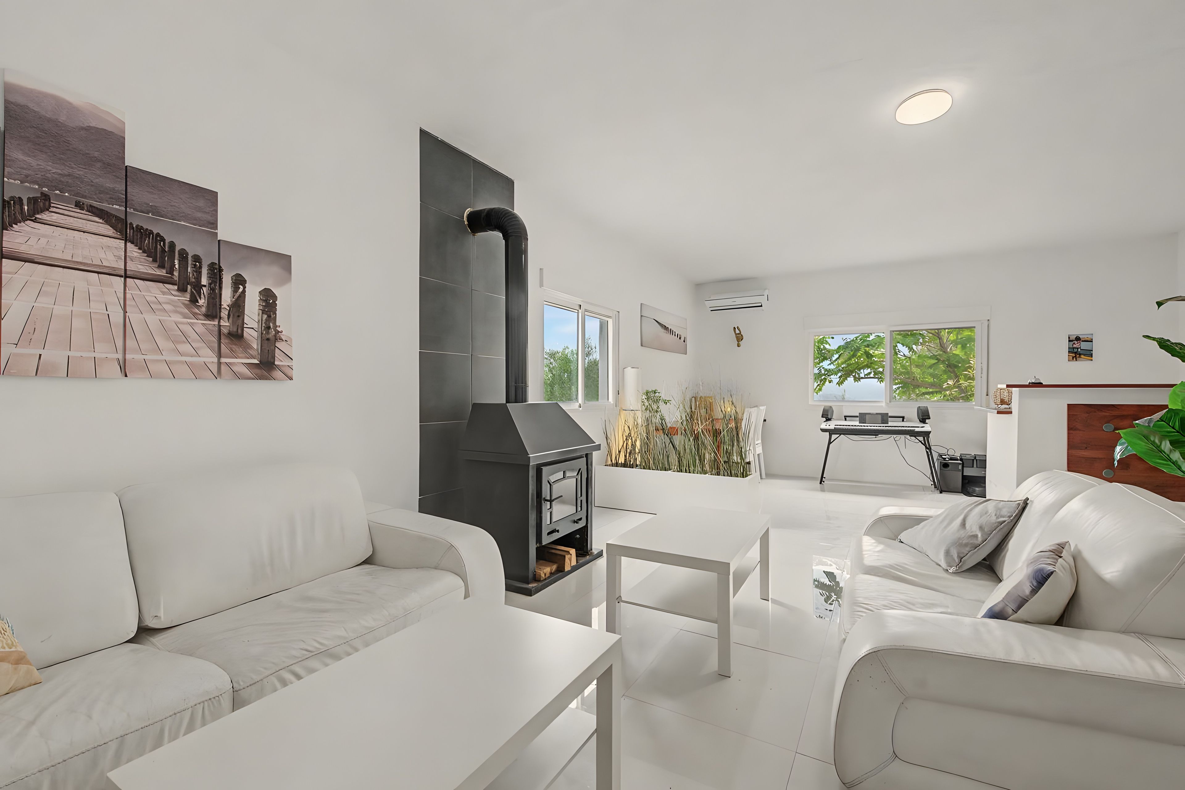 Een moderne woonkamer met een open haard, witte meubels en uitzicht op het buitenleven.