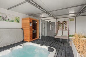 Een wellnessruimte met een jacuzzi, houten sauna en een douchecabine.