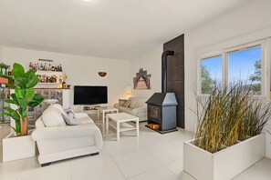 Een moderne woonkamer met een flatscreen televisie, een bank, een salontafel, een open haard en een groot raam met uitzicht.