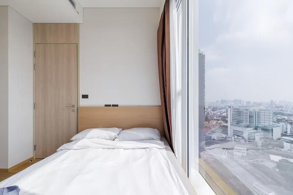 A bedroom with a bed, a wardrobe, and a window with a city view.