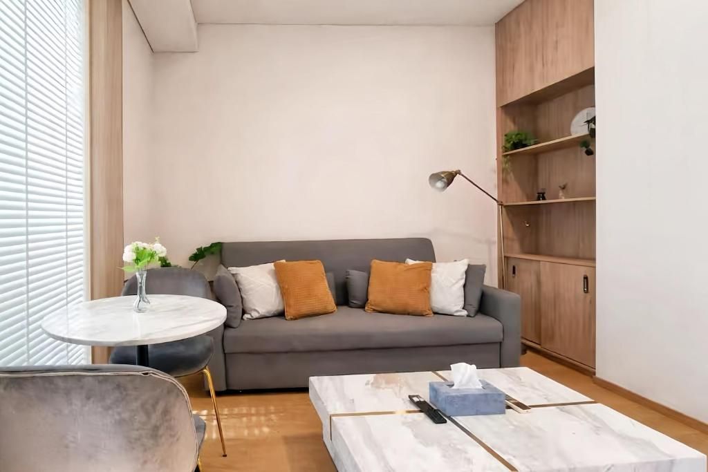 A modern living room with a grey sofa, a round coffee table, and a small side table with a vase.