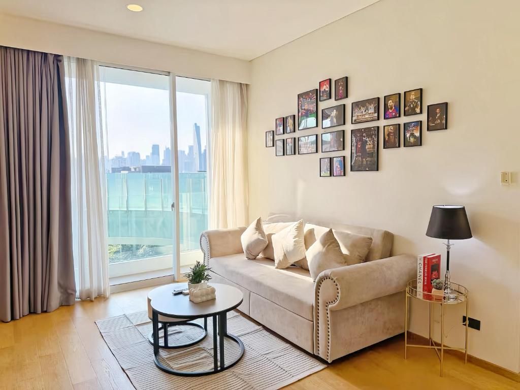 A living room with a sofa, a coffee table, a lamp, and a wall with framed pictures.