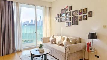A living room with a sofa, a coffee table, a lamp, and a wall with framed pictures.