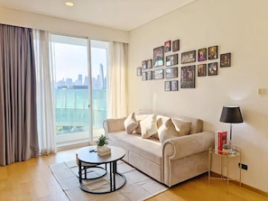A living room with a sofa, a coffee table, a lamp, and a wall with framed pictures. - Siamese Residence Sukhumvit 42 Bangkok (Krung Thep Maha Nakhon)