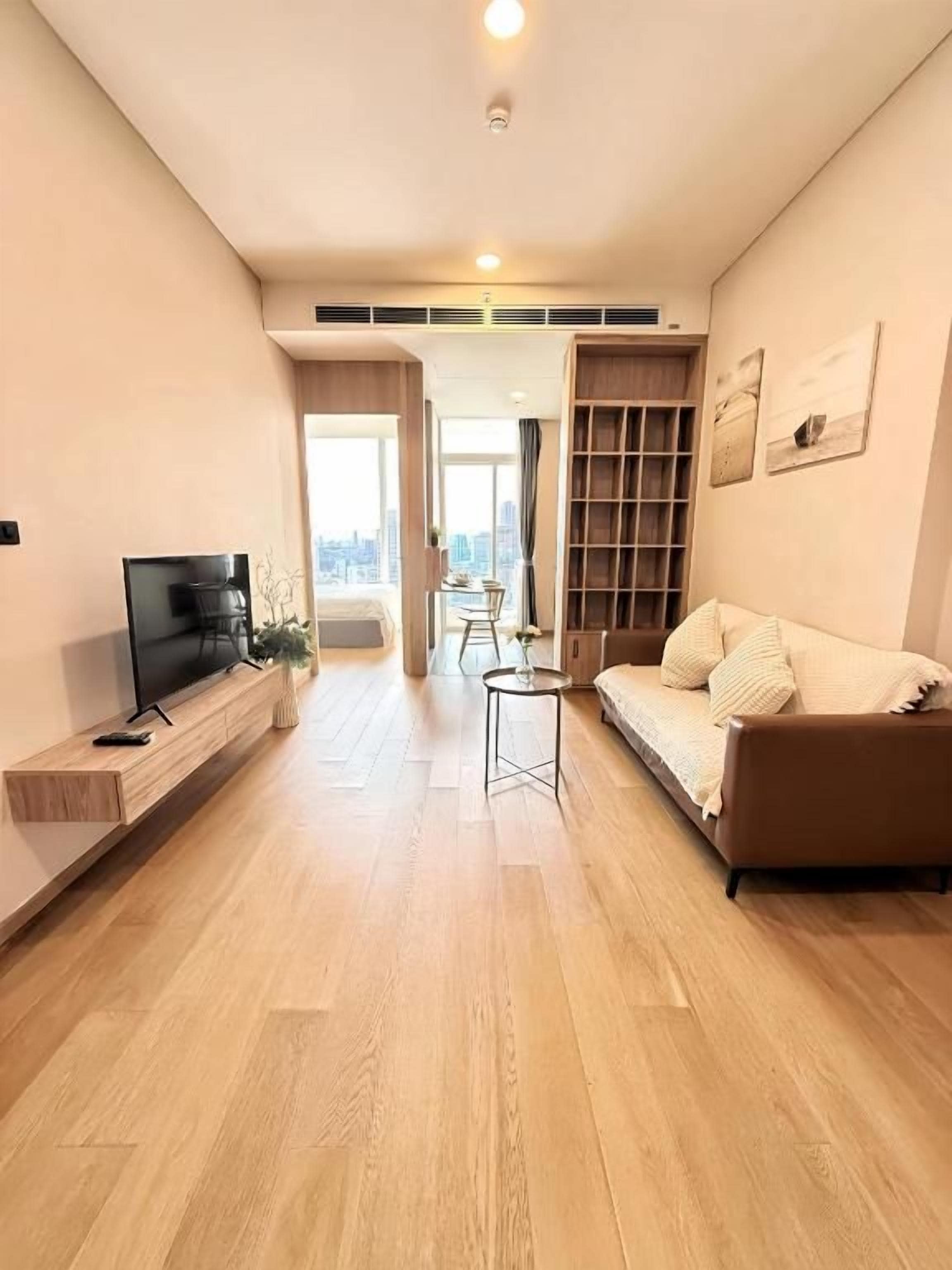 A modern living room with a flat-screen TV, a sofa, a coffee table, and a bookshelf.
