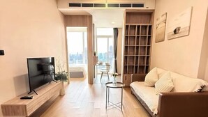 En moderne stue med et fladskærms-tv, en sofa, et sofabord og et bogreol.