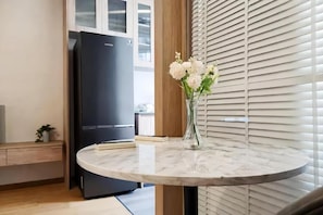 A kitchen with a marble countertop, a black refrigerator, and a vase with flowers on the counter. - Siamese Residence Sukhumvit 42 Bangkok (Krung Thep Maha Nakhon)