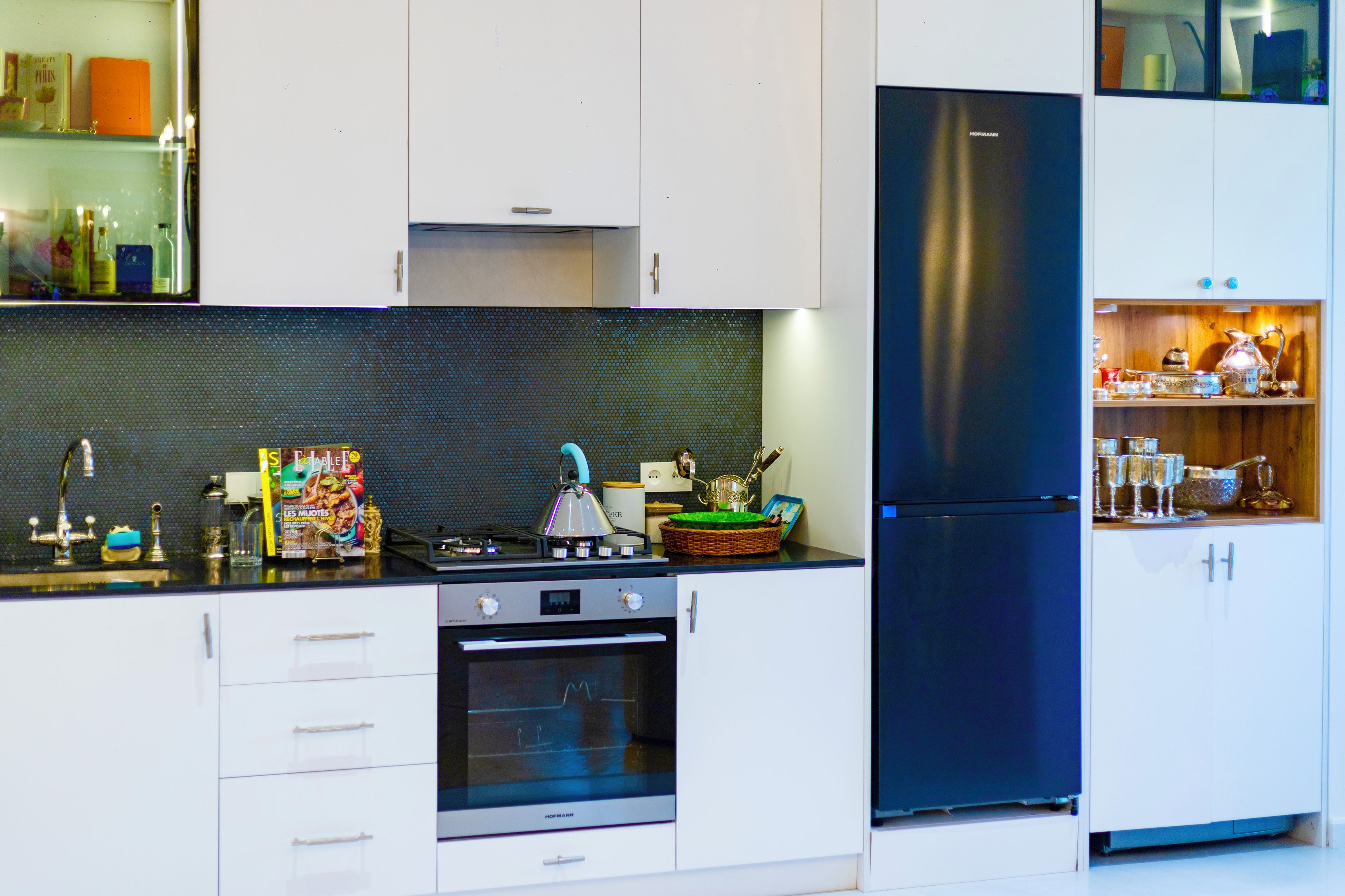 A modern kitchen with white cabinets, a black refrigerator, and a gas stove.