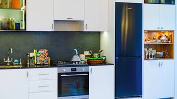 A modern kitchen with white cabinets, a black refrigerator, and a gas stove.