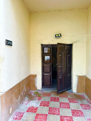 A building entrance with a tiled floor, a door, and a sign on the wall.