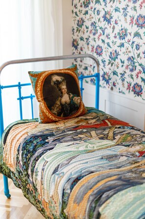 A bed with a blue metal frame, a quilt with a floral pattern, and a pillow with a portrait.
