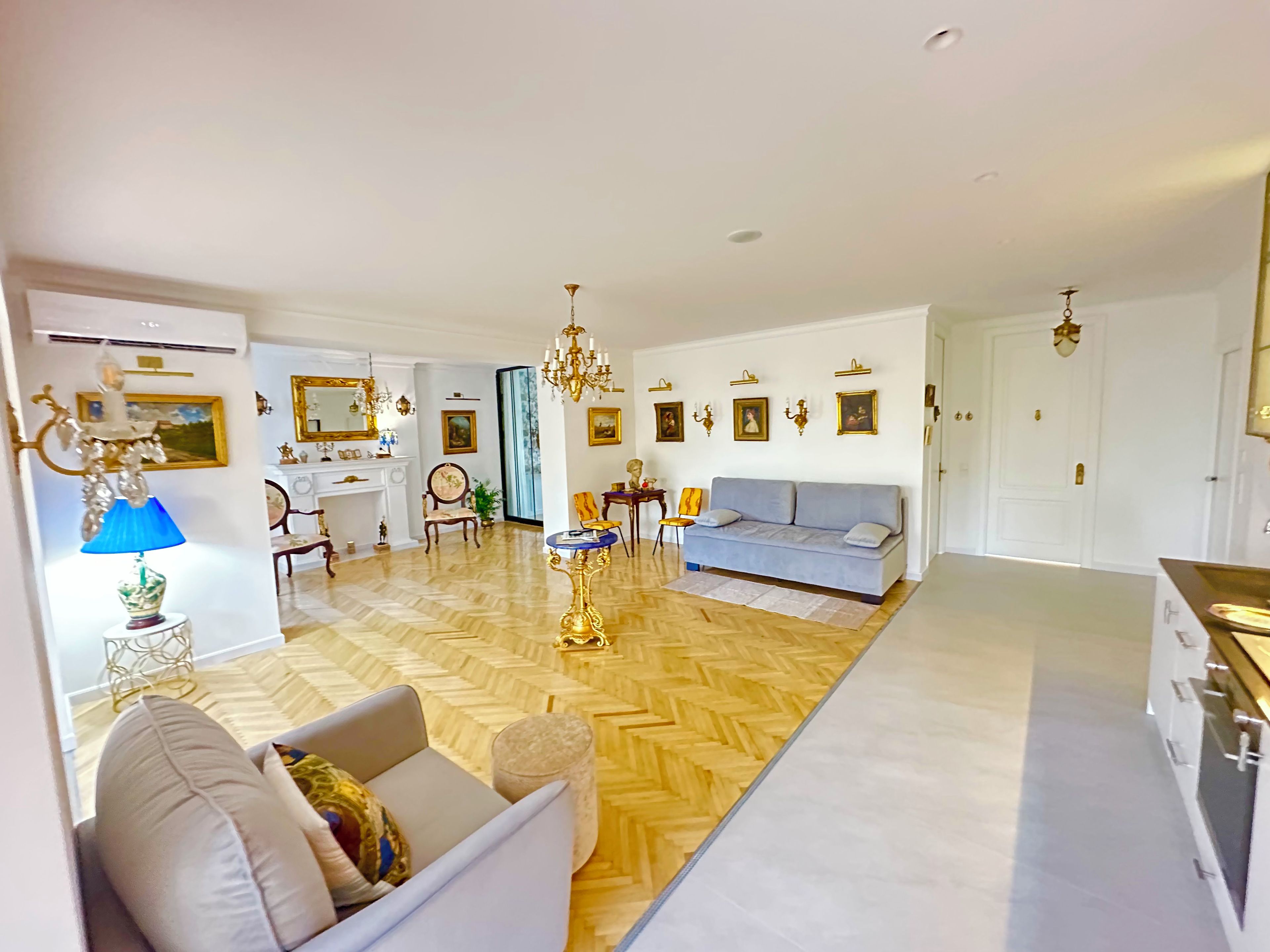 A spacious living area with a sofa, a dining table, and a chandelier.