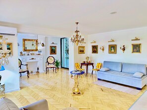 A spacious living room with a blue sofa, a chandelier, and a fireplace.