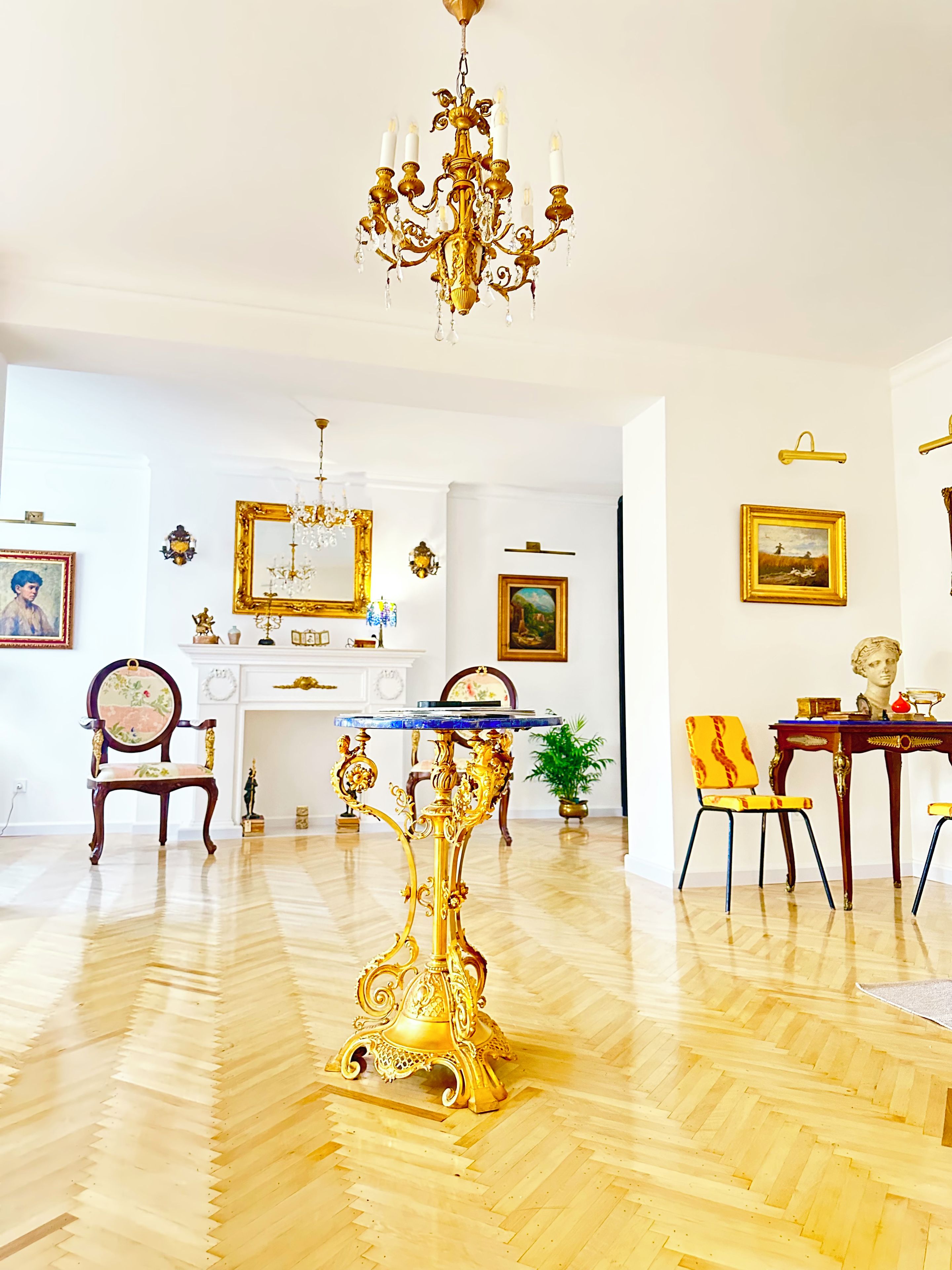 Une pièce avec un lustre, une table dont le plateau est bleu et une chaise à motifs jaunes et rouges.