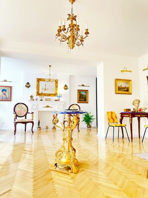 A room with a chandelier, a table with a blue top, and a chair with a yellow and red pattern.