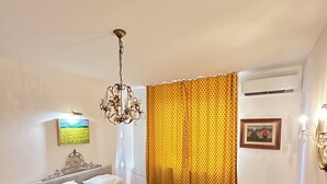 Une chambre à coucher avec un lit, un lustre, un tableau et un rideau à motifs.