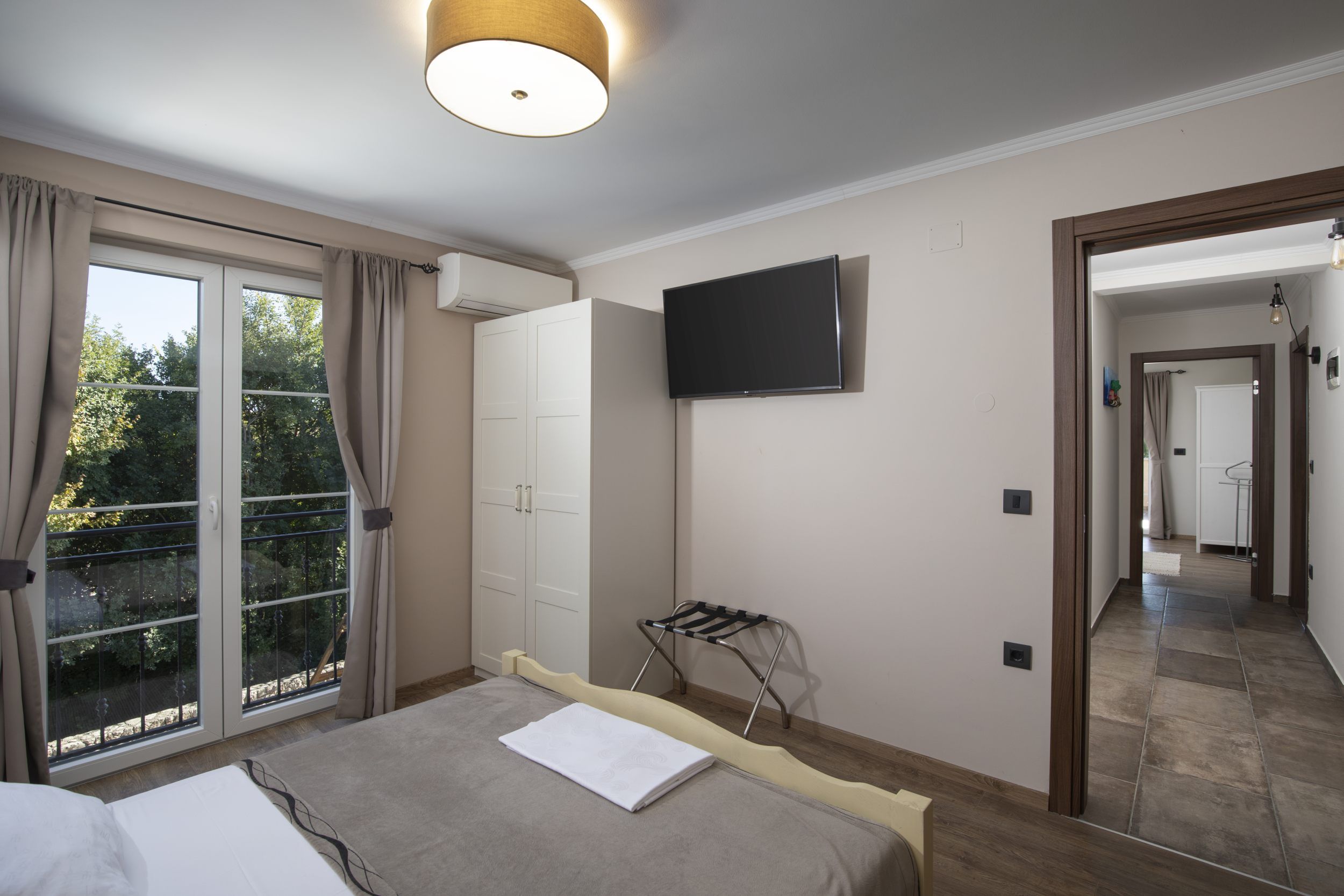 A bedroom with a bed, a television, and a sliding glass door to a balcony.