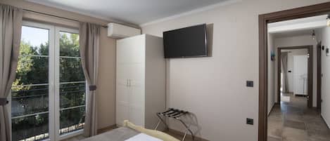 A bedroom with a bed, a television, and a sliding glass door to a balcony.