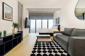 A modern living room with a large window, a flat-screen TV, a grey sofa, a black and white patterned rug, and a minimalist coffee table. - w* | Enchanting Loft in Juarez w/ Pool (Ciudad de México)