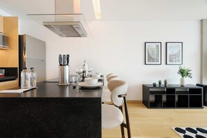 A modern kitchen with a central island, a dining area with a black console table, and two framed pictures on the wall. - w* | Enchanting Loft in Juarez w/ Pool (Ciudad de México)